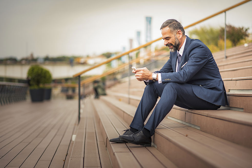 Person in suit sitting outside using phone